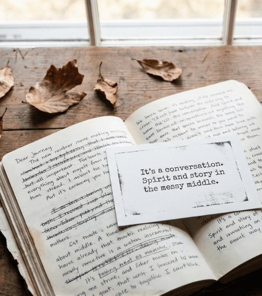 An open handwritten journal with a card reading “It’s a conversation. Spirit and story in the messy middle.”